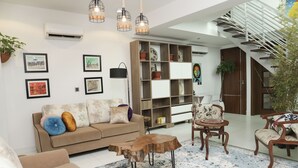 A modern living room with a sofa, coffee table, and chairs, a wooden bookshelf, and a staircase. - Cozy bohemian loft in the heart of Lekki. Close to the beach, art gallery & mall (Lekki)