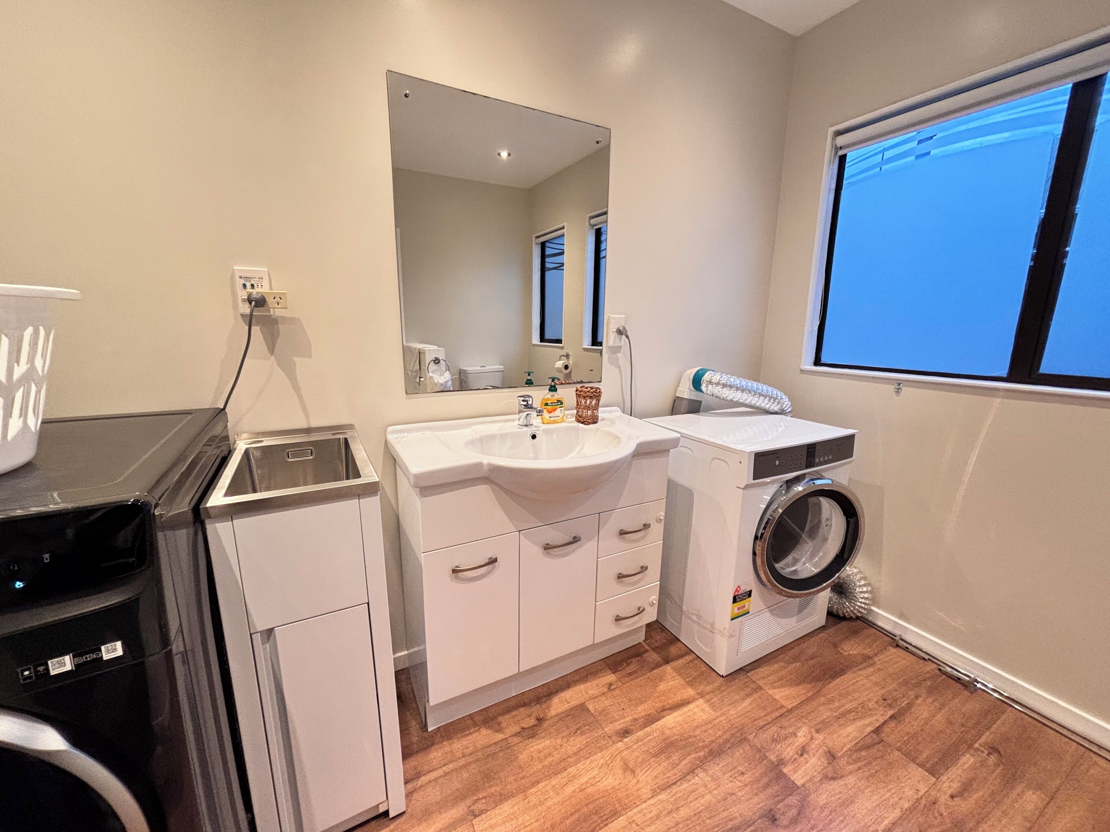 A compact bathroom with a sink, mirror, and washing machine.