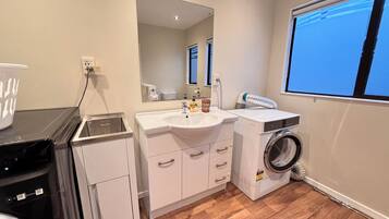A compact bathroom with a sink, mirror, and washing machine.