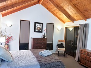 A bedroom with a bed, dresser, chair, and a sliding glass door. - 6 Bedroom Family Gateway in the Heart of Mapua Village (Māpua)