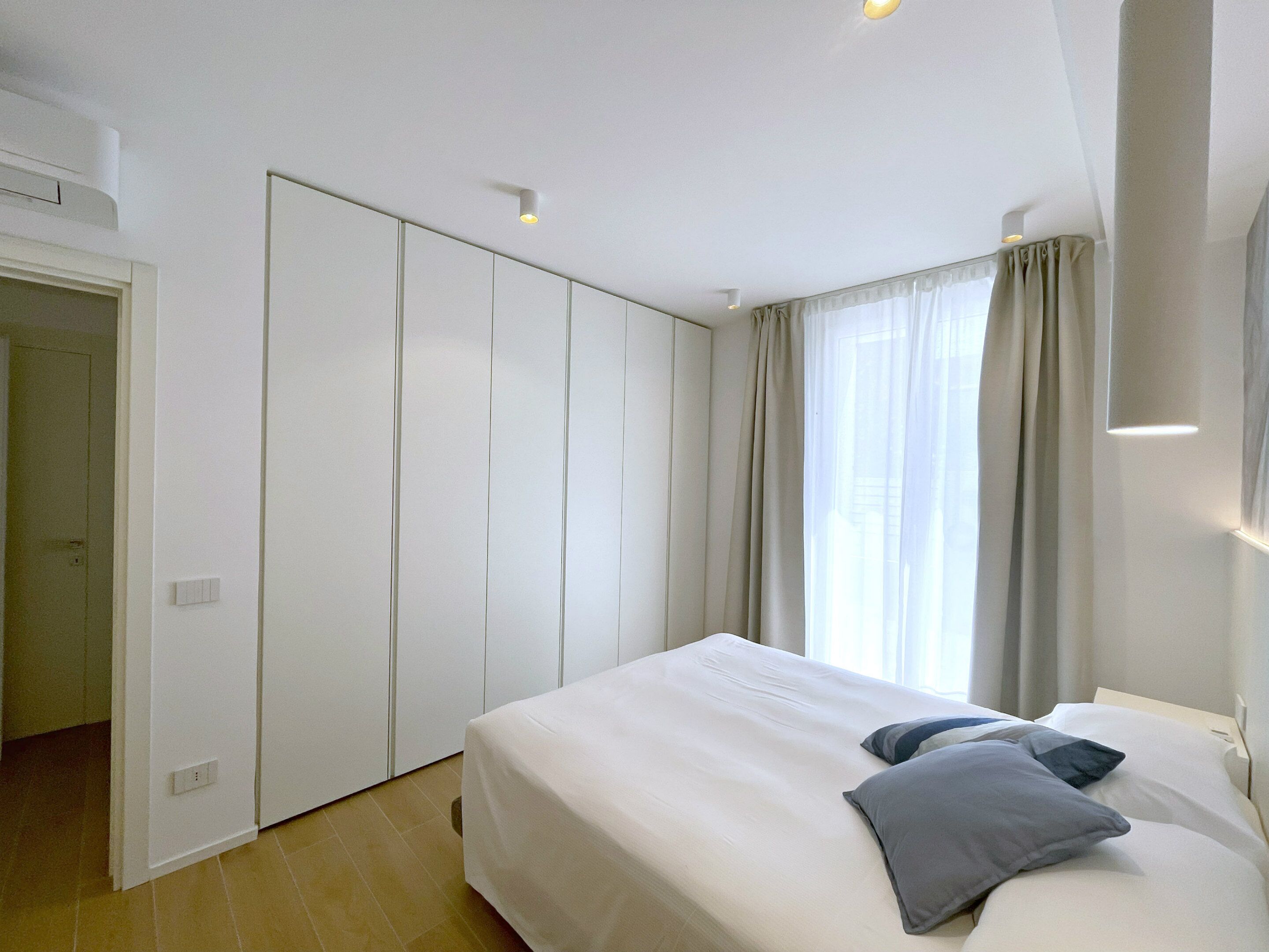 Un dormitorio con cama, armario y ventana con cortinas.