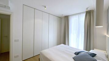 Un dormitorio con cama, armario y ventana con cortinas.