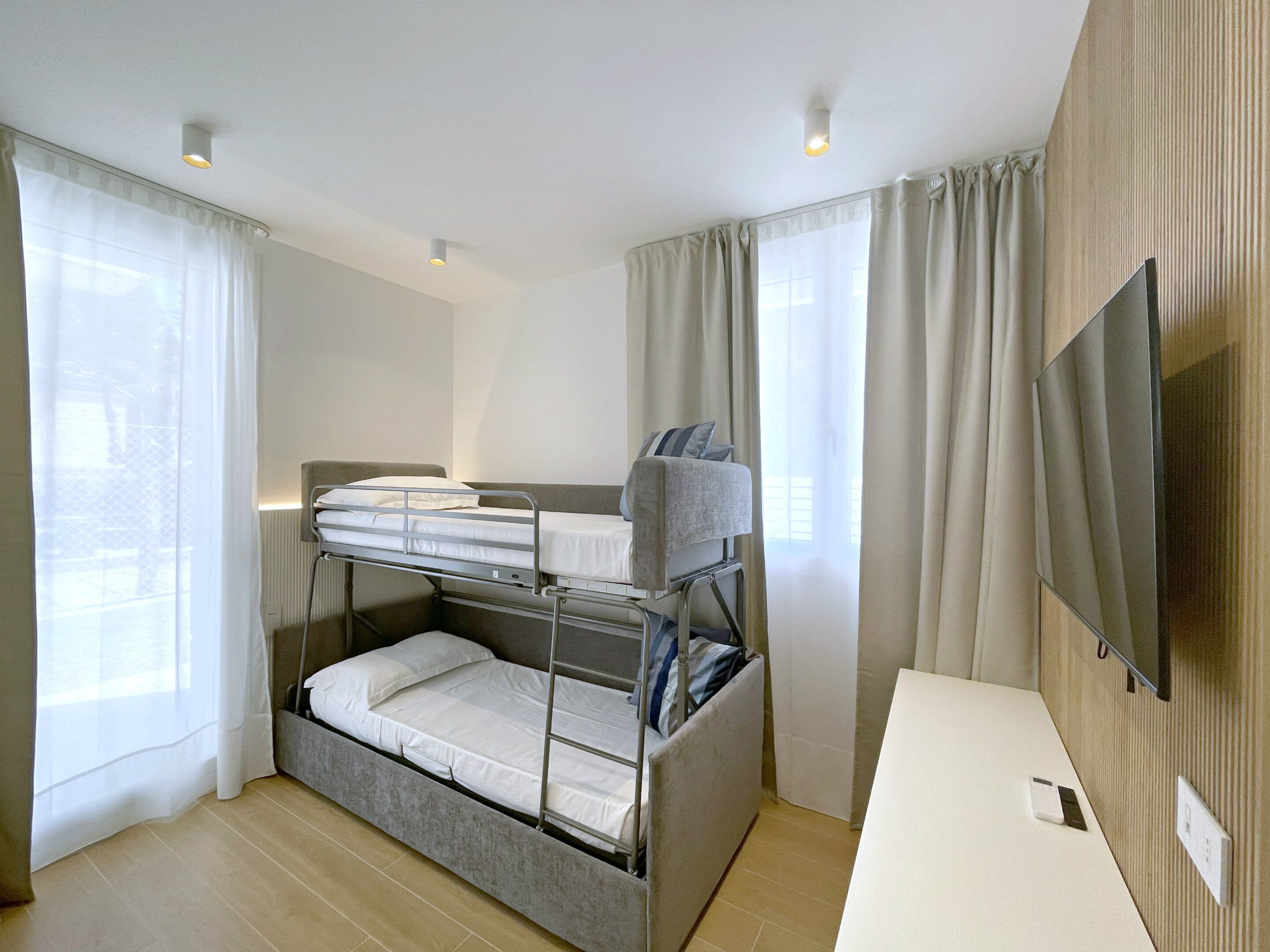 A bunk bed room with a flat-screen TV and a desk.