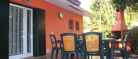 An outdoor patio with a table and chairs, a sliding glass door, and a red chimney.