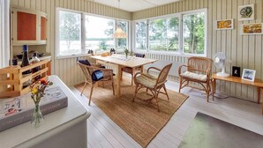 A dining area with a wooden table, wicker chairs, and a large window with a view of trees. - Awesome home in älmhult with lake view (Älmhult)
