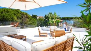 A rooftop terrace with white cushioned seating, wooden tables, and a large umbrella. - 1 bedroom pet friendly apartment in Pineto (Pineto)