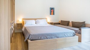 A modern bedroom with a large bed, a sofa, and a nightstand with a lamp. - 1 bedroom pet friendly apartment in Pineto (Pineto)