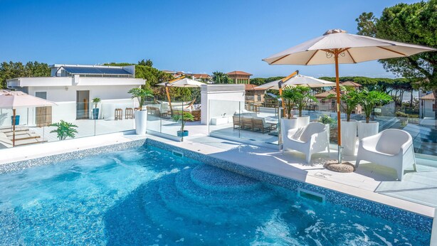 A modern pool area with clear blue water, white lounge chairs, and umbrellas. - 1 bedroom pet friendly apartment in Pineto (Pineto)
