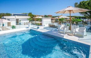 A modern pool area with clear blue water, white lounge chairs, and umbrellas. - 1 bedroom pet friendly apartment in Pineto (Pineto)