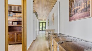 Un pasillo con una estantería de madera, un banco rústico y un cuadro enmarcado en la pared.