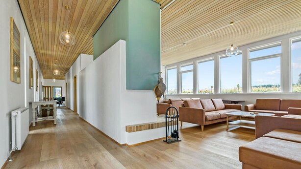 Un amplio salón con techo de madera, ventanas grandes y una disposición de asientos.