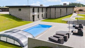 Un edificio moderno con piscina, zona de estar al aire libre y una estructura tipo invernadero.
