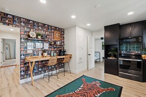 A modern kitchen with dark cabinets, a microwave, and an oven. There is a dining area with a wooden table and chairs. - Das Green Dor - Sleeps 9, Hot Tub & Fire Pit (Fredericksburg)