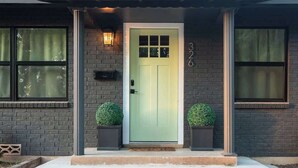Una casa con puerta verde, fachada de ladrillo y el número 326 en la pared.