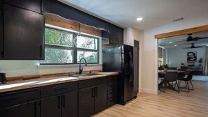 Una cocina moderna con muebles oscuros, un refrigerador de acero inoxidable y un ventanal que proporciona luz natural.