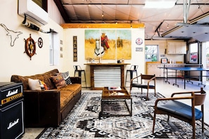 Um quarto com sofá de couro, mesa de centro, área de bar e um quadro na parede.
