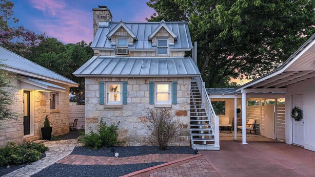 A stone house with a metal roof, a brick pathway, and a staircase leading to a covered area. - Stonewall Bungalow 3 - Sleeps 4 (Stonewall)