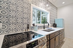 Una cucina con carta da parati decorata, una finestra, un fornello e un frigorifero.