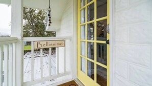Un porche con una puerta amarilla, una campana colgante y un letrero que dice 'Bellissimo'.