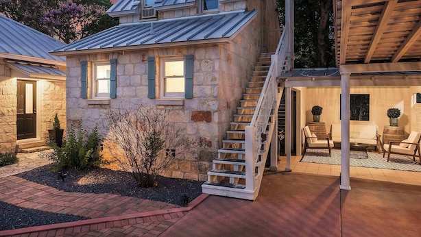 Una casa de piedra con una escalera que lleva a un porche cubierto.