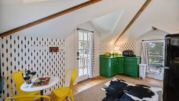 A dining area with a table and chairs, a kitchen with green cabinets, and a cowhide rug.
