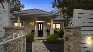 Talo, jossa on kiviverhous, katettu kuisti ja portilla varustettu sisäänkäynti.