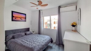 A bedroom with a bed, a ceiling fan, a window with curtains, and a wall-mounted air conditioner. - Awesome apartment in Puerto de Mazarron (Puerto de Mazarron)