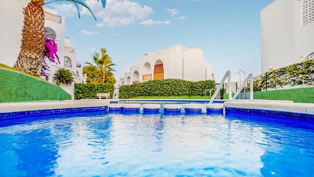 A swimming pool with clear blue water, surrounded by white buildings and greenery. - Awesome apartment in Puerto de Mazarron (Puerto de Mazarron)