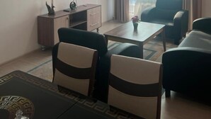 A modern living room with a flat-screen TV, a wooden cabinet, a coffee table, and two sofas. - Zeraviktoria (Atyrau)