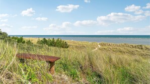 Eine Küstenlandschaft mit einer Wiese, einer verrosteten Bank und freiem Blick auf das Meer.