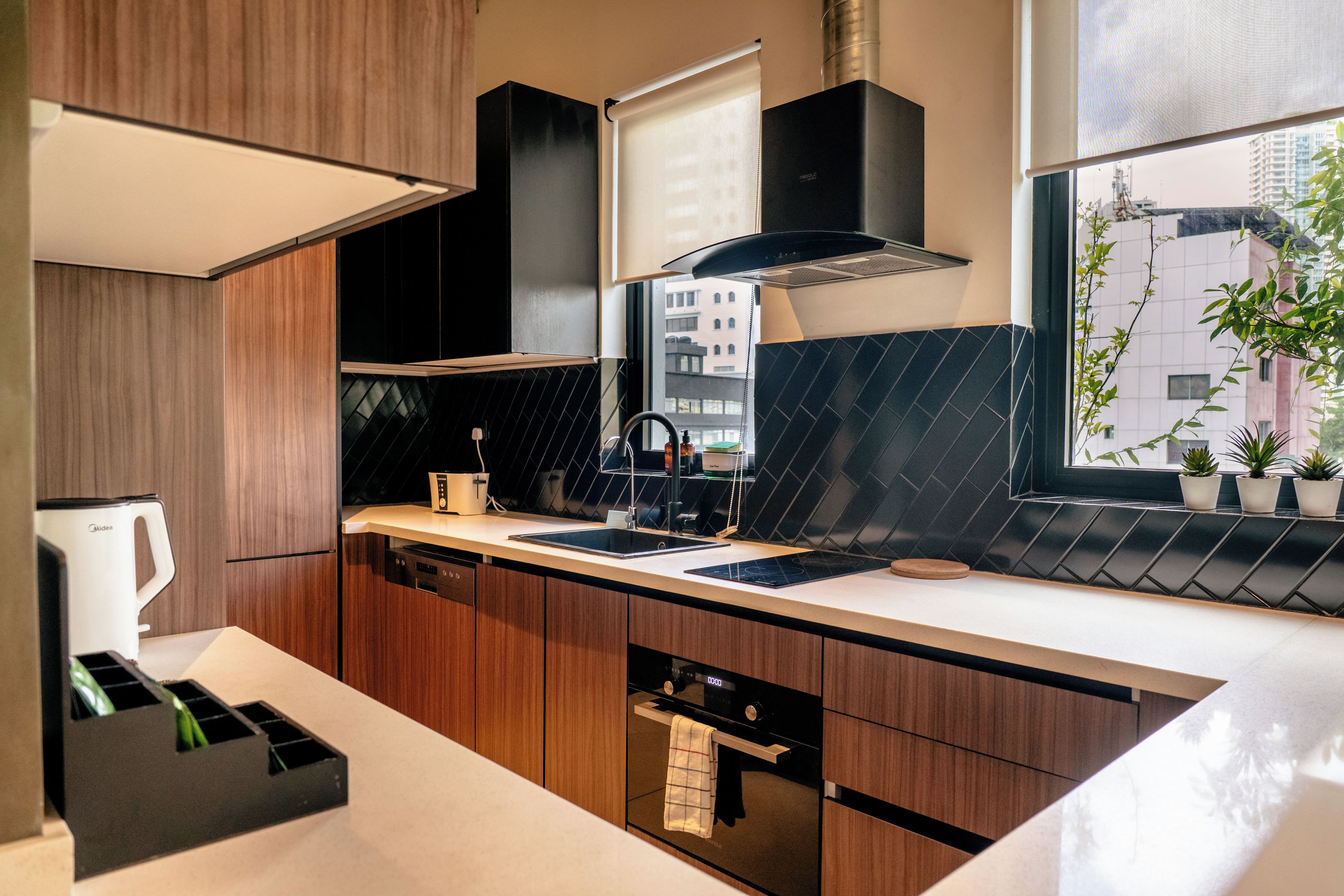 A modern kitchen with a built-in oven, a coffee maker, and a window with a view of buildings.