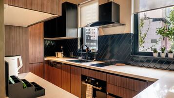 A modern kitchen with a built-in oven, a coffee maker, and a window with a view of buildings.