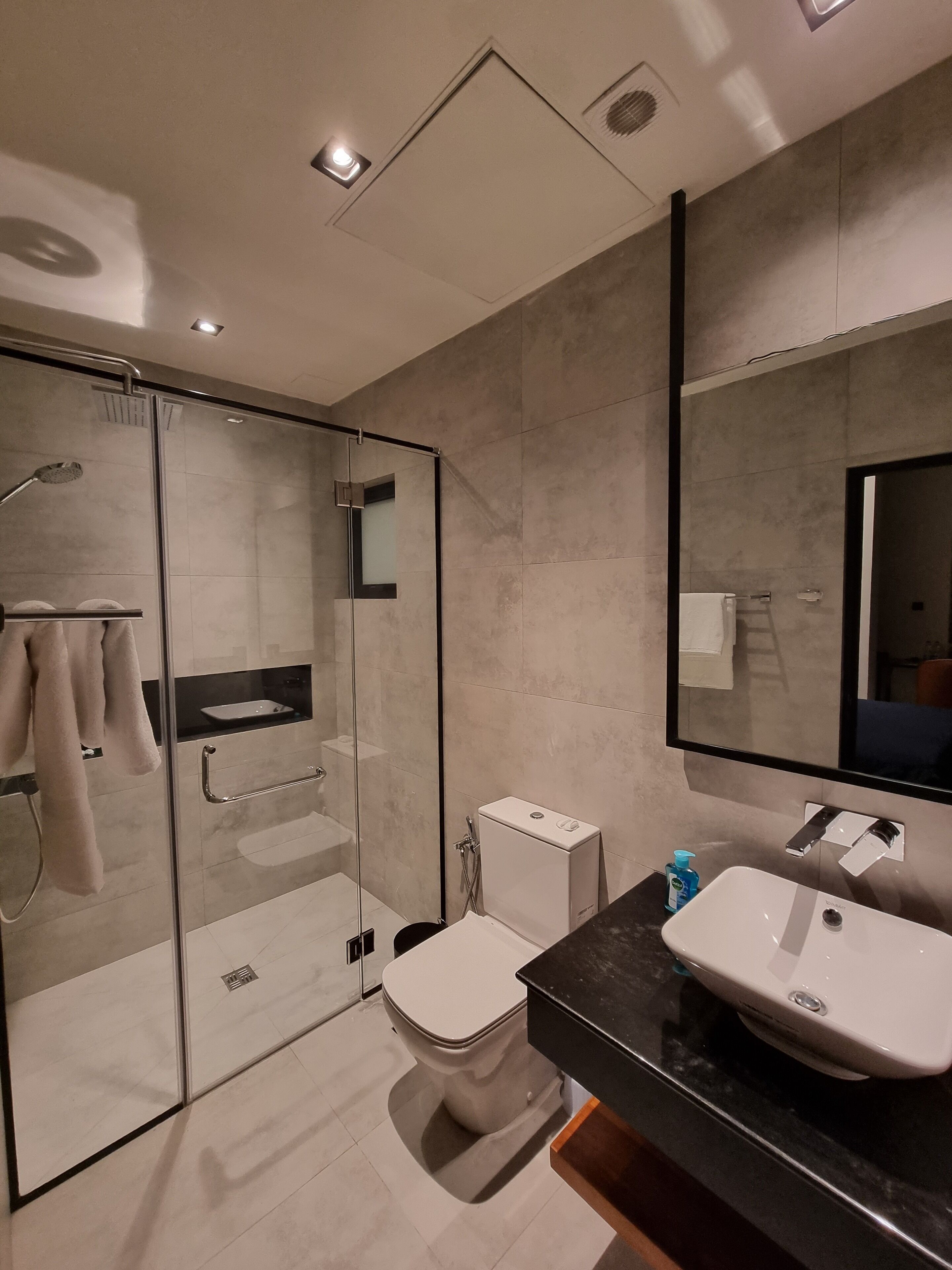 A modern bathroom with a glass-enclosed shower, a white toilet, and a black countertop with a sink.