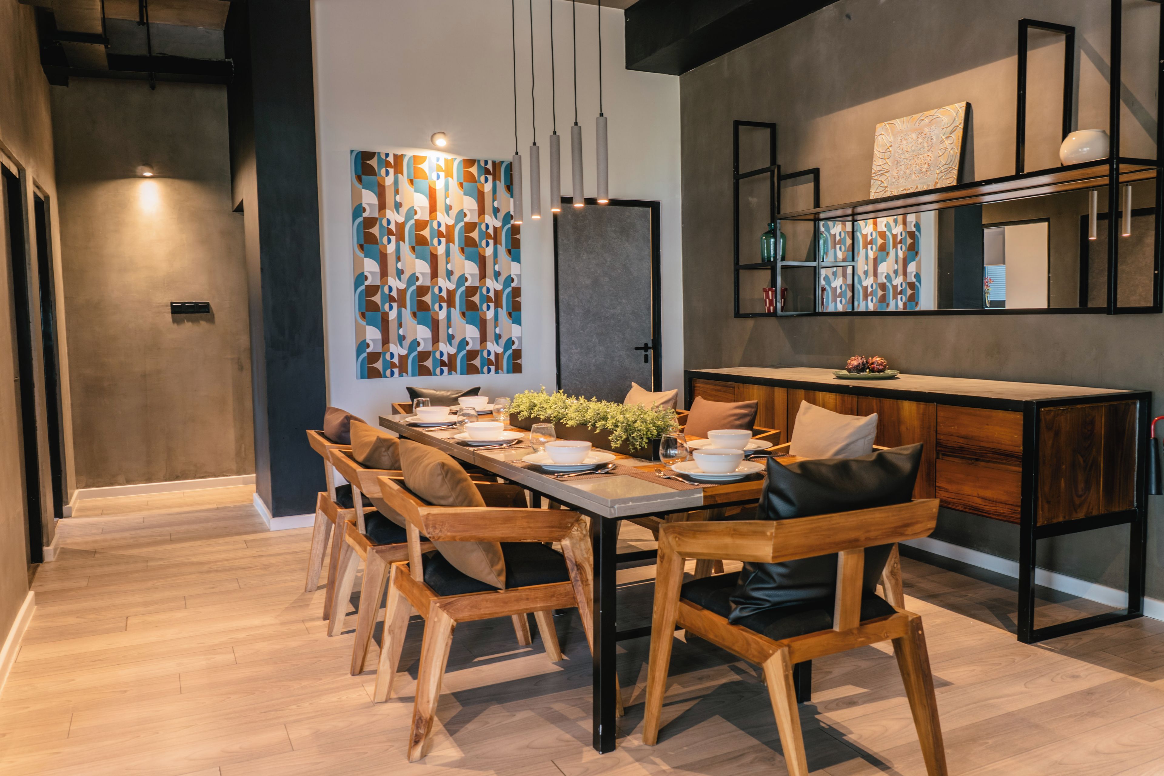 A modern dining area with a long wooden table, multiple chairs, and a central plant.