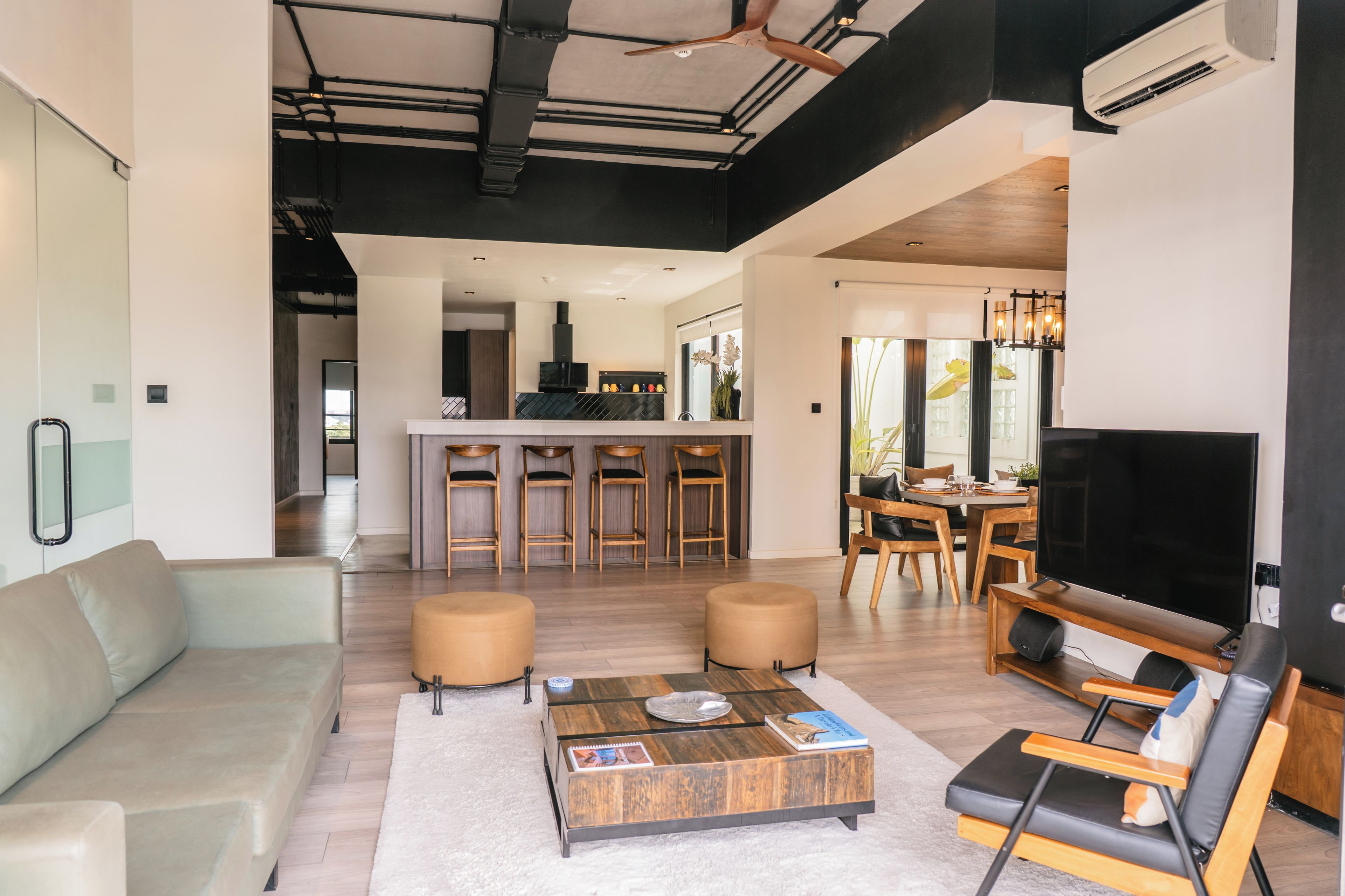 A modern living space with a sofa, coffee table, TV, and a dining area with chairs and a table.