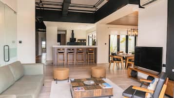 A modern living space with a sofa, coffee table, TV, and a dining area with chairs and a table.