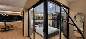 A modern bedroom with a glass partition, a bed, a desk, and a dining area. - LView Acropolis (Athens)