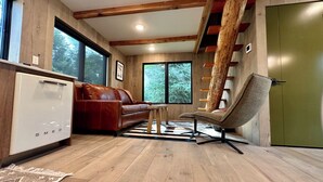 Un intérieur moderne avec un plancher en bois, un canapé en cuir marron, une chaise en bois et une porte verte.