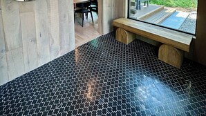 Un intérieur en bois avec une table ronde, des chaises et un banc près d’une grande fenêtre.