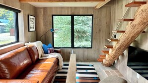 Un salon moderne avec un canapé en cuir, une table basse en bois et un escalier original au revêtement en bois naturel.