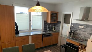 A modern kitchen with wooden cabinets, a built-in oven, and a dining area with a table and chairs.