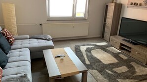A living room with a sofa, a coffee table, a TV, and a radiator.