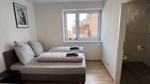 Un dormitorio con cama, ventana y zona de ducha.