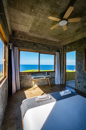 A bedroom with a bed, a desk, and a view of the ocean. - Izustarri (Burgos)