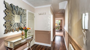 A hallway with a modern mirror, a glass console table with flowers, a coat rack, and a radiator. - Stunning 2-bed Apartment in Windsor - Free Parking (Windsor)