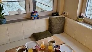 A cozy breakfast setup with a table, breakfast items, and a view of a snowy landscape through a window.