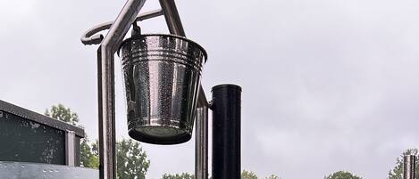 A portable toilet with a metal frame, a bucket, and a faucet.