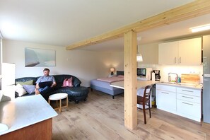 Een ruimtelijk ingerichte leefruimte met kitchenette, eethoek en zithoek.