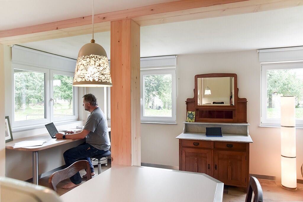 A modern kitchen with a wooden dining table, a laptop on the counter, and a pendant light.
