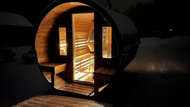A cozy, circular wooden structure with a warm interior, a bench, and a view of the snowy landscape outside.